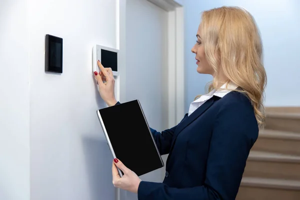 一个全神贯注的女人按下墙上数字装置上的按钮的侧视图 — 图库照片