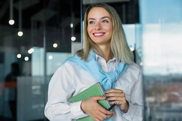 At the office. Blonde smiling woman with a notebook