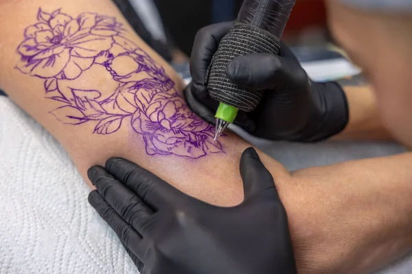 在纹身沙龙里纹身大师在女人手臂上画纹身 — 图库照片