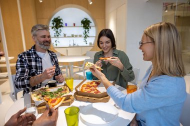 Pizza zamanı. Birlikte yemek yiyip pizza yiyen bir grup insan.