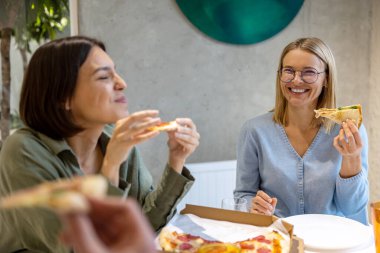 Öğle yemeği vakti. Arkadaşlar öğle yemeğinde eğleniyorlar ve pizzanın tadını çıkarıyorlar.