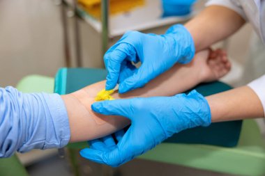 Klinikteki tanınmayan küçük kız ilaçlı damlatıcı kullanıyor, doktor şırınga kullanıyor ve hasta hastanede yatıyor..