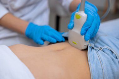 Doktor, klinikteki sonogram cihazıyla çocuk karın boşluğunu inceleyen okul çağındaki kız tıp uzmanına ultrason taraması yapıyor..