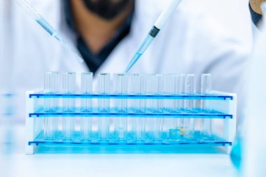 Tanımlanamayan erkek bilim adamı tıp laboratuarında, araştırma ve modern araştırmada pipet ve cam damlatıcı kullanıyor..