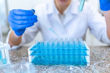 Şişede sıvıyla çalışan tanınmayan kadın bilim adamı ya da doktor, laboratuardaki tıbbi örnekleri inceler..