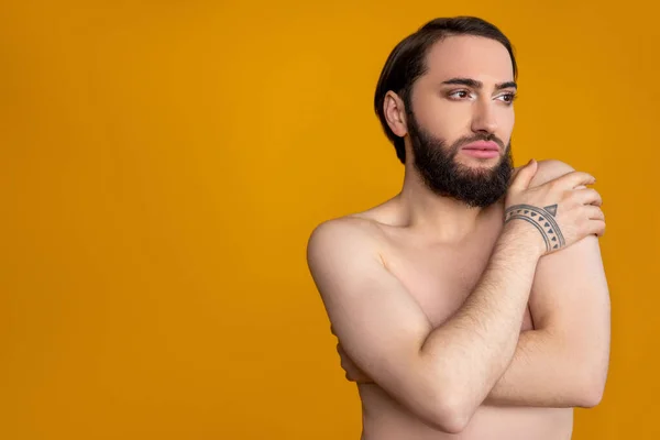 彼の体を隠し髭を生やして裸のトランスジェンダーの人を夢を見て 離れて見て プロモーションテキストのためのスペースをコピーし オレンジの背景に隔離されたポーズ — ストック写真
