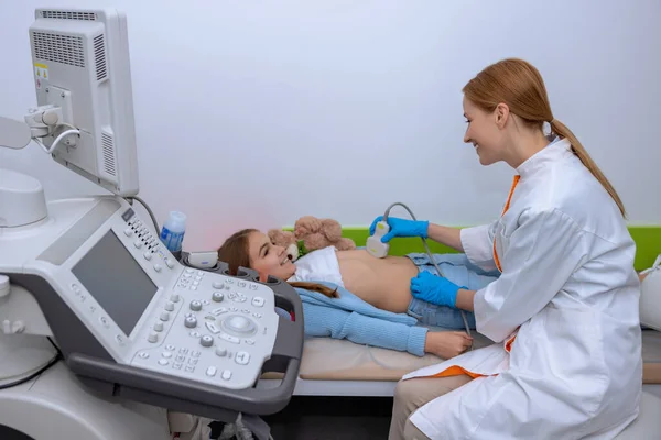 学校で超音波スキャンを行う医師女医専門医診療所でソノグラム機器で子どもの腹部空洞を調べる — ストック写真