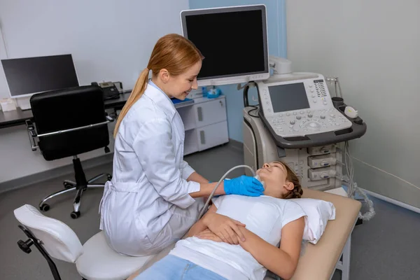 学校で甲状腺超音波検査を行う女性医師少女医療専門家病院でソノグラム機器で子供の首を検査 — ストック写真