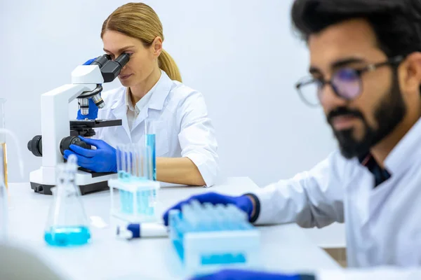 現代の研究室では 試料を調べる科学者 顕微鏡を使う女性医師 化学物質の液体を扱う男性研究者のチーム — ストック写真