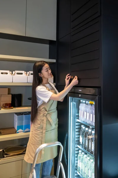 Gülümseyen Kafe Çalışanı Buzdolabının Üstündeki Duvara Içecek Dolu Mektupları Yerleştirirken — Stok fotoğraf