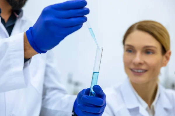 年轻男女科学家在医学实验室使用带试管的管道 共同研究医学样品蓝色液体 — 图库照片