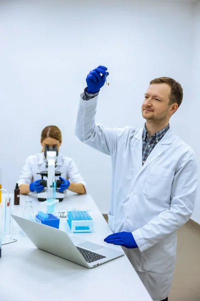 男性科学者は ビール中の液体を分析し コンピュータでの観察 顕微鏡で作業する女性研究者 一緒に医療サンプルを調査する同僚 実験を行う — ストック写真