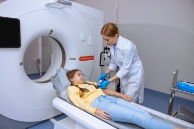 Bayan doktor çocuğun MRI taramasını yapıyor, çocuk için tomografi yapıyor, modern klinikte küçük kız sağlığını inceliyor..