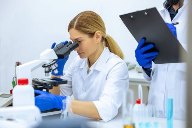 Laboratuvarda örnek test yaptıktan sonra notlar alan laboratuvar önlüklü kadın ve erkek bilim adamları profesyonel işçi analizlerine birlikte veri geldi..