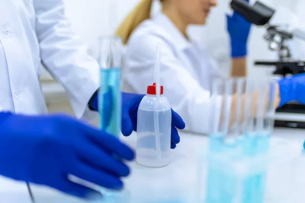 Oigenkännlig Forskare Bär Blå Gummihandskar Undersöka Vätska Provrör Laboratorium Kollega — Stockfoto