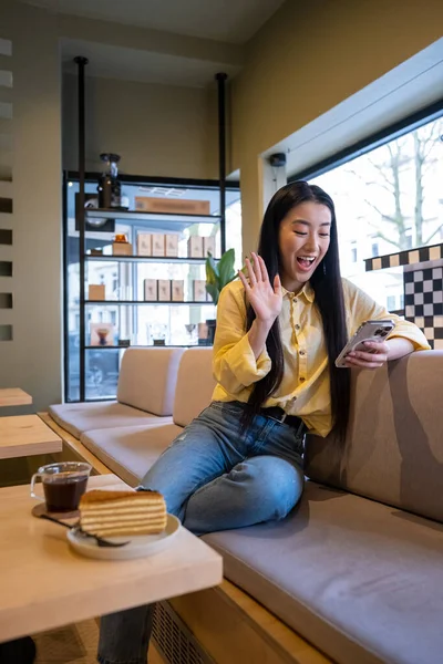 Lachend Vrolijke Jonge Vrouw Zittend Bank Aan Cafe Tafel Zwaaiend — Stockfoto