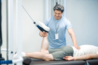 Aşırı genişleme. Rehabilitasyon merkezinde bacağını uzatan bir erkek hasta var.