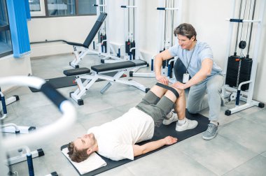 Rehabilitasyon. Tecrübeli bir eğitmen rehabilitasyon egzersizinde bir adama yardım ediyor.