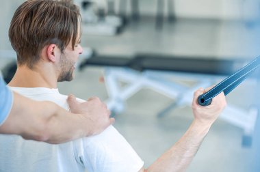 Fizik tedavi. Genç adam rehabilitasyon merkezinde eğitmenle fizik tedavi görüyor.