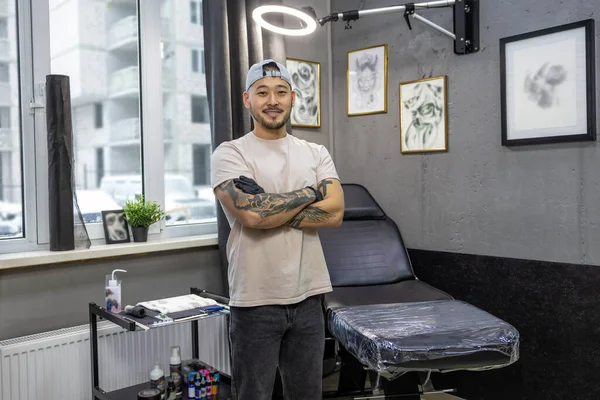 In the tattoo salon. Asian young man standing in the tattoo salon
