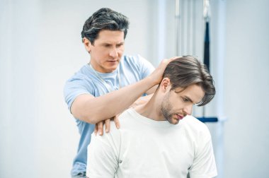 Boyun rehabilitasyonu. Hasta boynu üzerinde çalışan fizyoterapist.