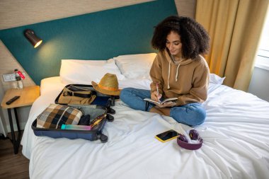 Tatile hazırım. Genç kıvırcık saçlı kadın tatile hazırlanıyor ve mutlu görünüyor.