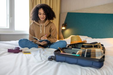 Tatile hazırım. Genç kıvırcık saçlı kadın tatile hazırlanıyor ve mutlu görünüyor.