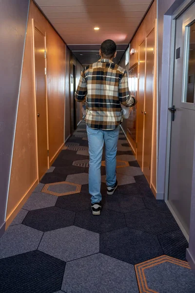 在酒店里穿着格子呢衬衫的年轻人在酒店走廊里 — 图库照片