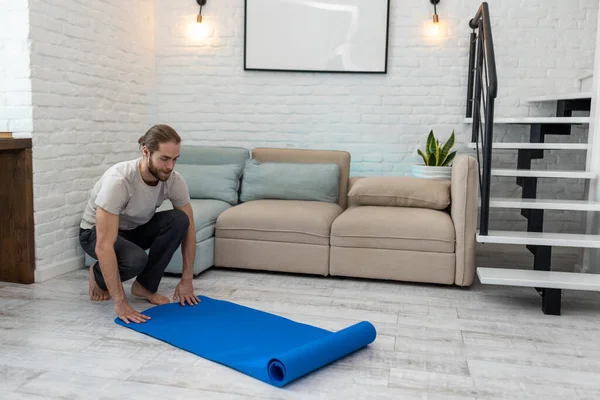 Atletik Adam Evde Egzersiz Yapmaya Hazırlanırken Yoga Minderini Açıyor — Stok fotoğraf