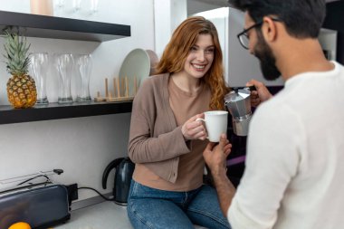 Sevgi dolu bir çift, mutfakta birlikte kahve içmekten zevk alıyor. Aşklarını ifade ediyorlar..