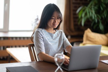 Serbest meslek. Koyu renk saçlı genç bir kadın dizüstü bilgisayarda çalışıyor ve olaya dahil gibi görünüyor.