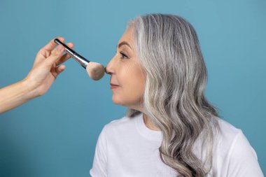 Güzellik ipuçları. Güzel gülümseyen son sınıf kadını makyaj yapıyor.