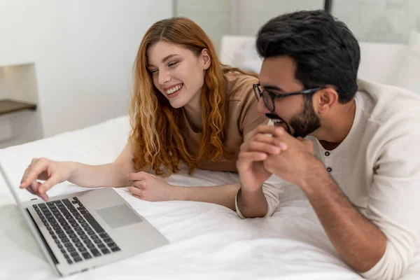 幸せな妻と夫はベッドルームでラップトップを使用して インターネットを一緒にブラウジングしたり 映画を見たり — ストック写真