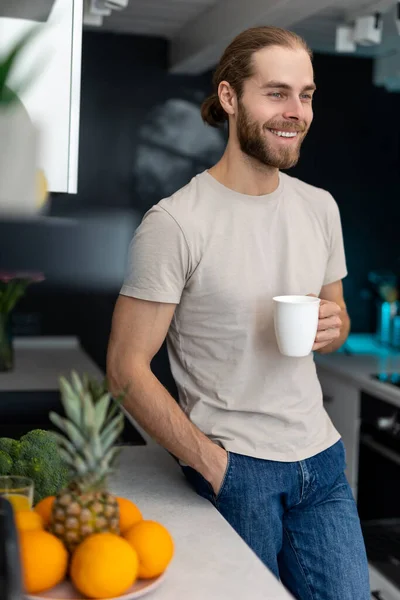 Усміхнений Молодий Дорослий Чоловік Бородою Тримає Чашку Кавою Стоїть Кухонній — стокове фото