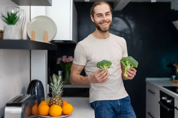 Усміхнений Чоловік Тримає Зелену Свіжу Брокколі Стоїть Сучасній Кухні Вдома — стокове фото