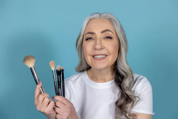 Beauty tips. Beautiful smiling senior woman doing makeup
