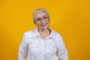 Sarı arka planda bir kadın. Sarı arka planda duran uzun saçlı, güzel yaşlı kadın.