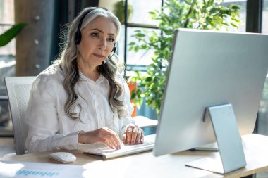 Proje üzerinde çalış. Bilgisayardaki yakışıklı, olgun iş kadını meşgul görünüyor.