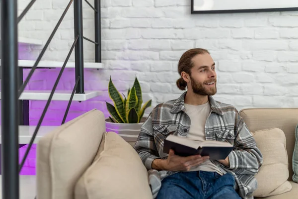 Handsome Smiling Happy Young Man Reading Book While Sitting Sofa — Stock Photo, Image