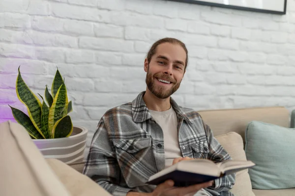 Alegre Hombre Sonriente Leyendo Libro Mientras Está Sentado Tos Casa — Foto de Stock