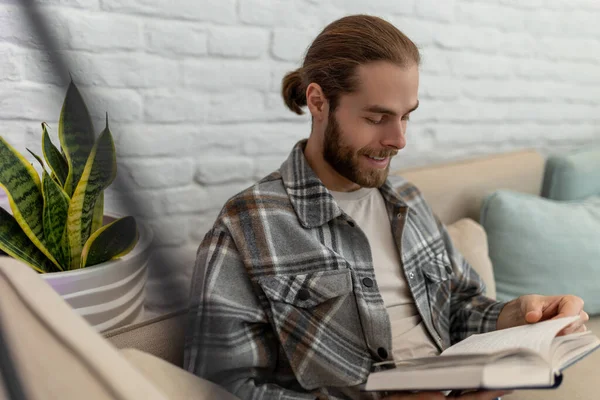Handsome Smiling Happy Young Man Reading Book While Sitting Sofa — Stock Photo, Image