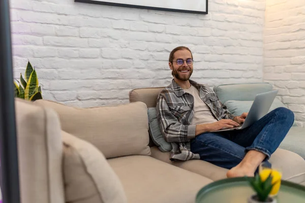 Young Attractive Smiling Guy Glasses Browsing His Laptop Sitting Sofa — Stock Photo, Image