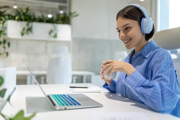 Fröhliche Büroangestellte Mit Kopfhörern Schreibtisch Sitzend Und Auf Den Computermonitor — Stockfoto