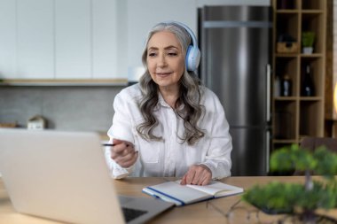 Giyin. Bilgisayarın başında gülümseyen yaşlı kadın Webinar dinliyordu.