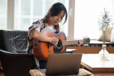 Çevrimiçi müzik dersi. Genç Asyalı kız online gitar dersi alıyor.
