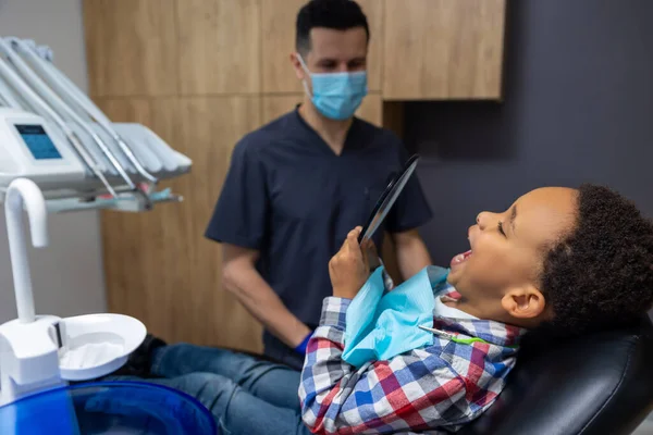 Dişçilere Esmer Tenli Çocuk Aynada Dişlerine Bakıyor — Stok fotoğraf
