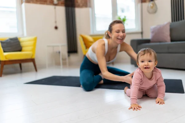 stock image Healthy development. Athletic mother and baby girl exercising together at home playing in living room.