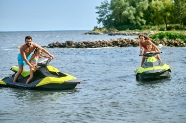 Baba, anne, kız ve oğul jet-ski 'lerde yarışıyorlar okyanusta deniz araçlarının keyfini çıkarıyorlar, aktif yaz zamanı..