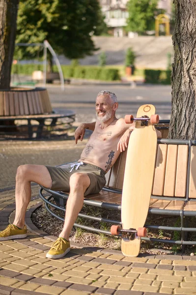 Spokojen Dospělý Muž Longboardem Sedí Lavičce Městském Parku — Stock fotografie