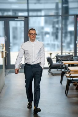 Kapalı dizüstü bilgisayarı olan, beyaz gömlekli bir iş adamı mola vermek için kafeye gidiyor..